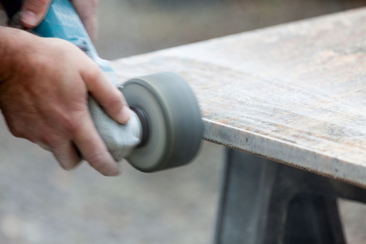 Granit Schleifwerkzeug im Einsatz. Ein Handwerker beim Einsatz eines WInkelschleifers und einer Schleifscheibe für Granit